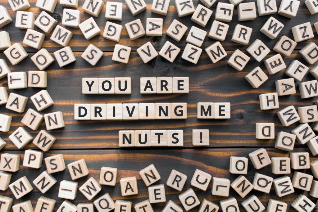 You are driving me nuts - phrase from wooden blocks with letters, to make someone very annoyed concept, random letters around, white  background