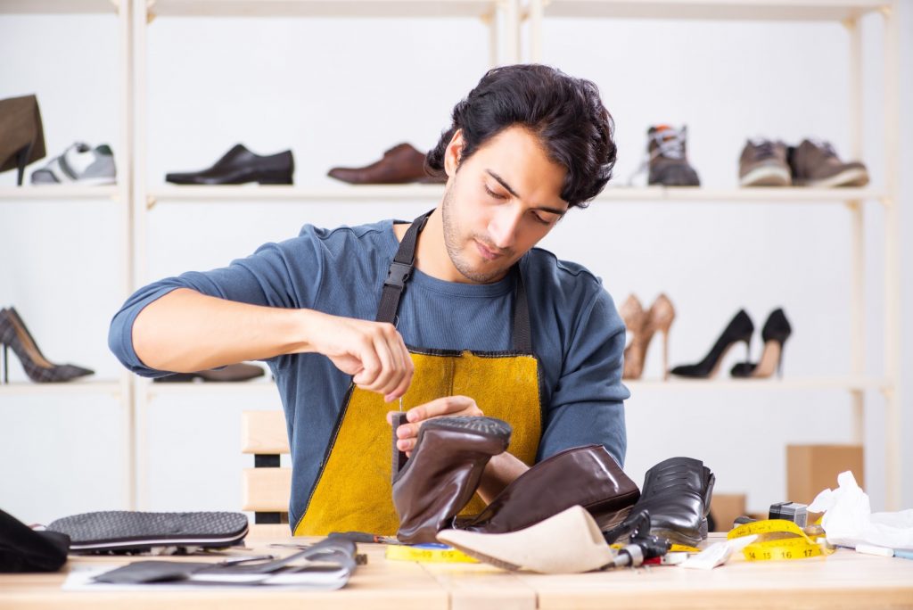 Young man repairing shoes in workshop