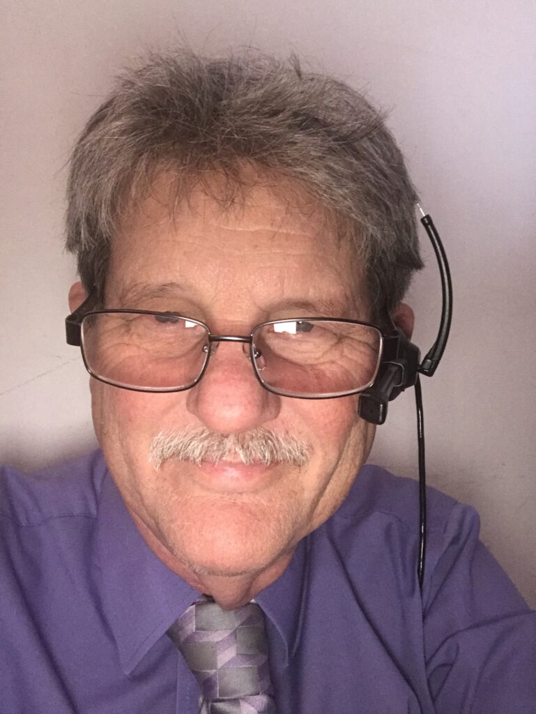 John Grubb wearing headset and reading glasses